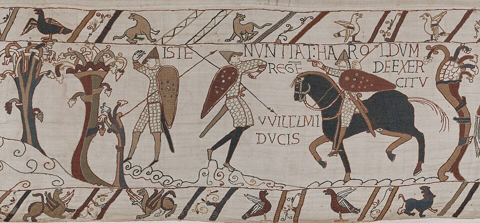 Panneau brodé de la Tapisserie de Bayeux : deux messagers et un cavalier, encadrés d'une inscription latine et des frises d'animaux.